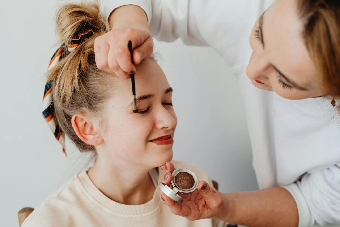 Photo by Karolina Kaboompics: https://www.pexels.com/photo/woman-doing-makeup-for-smiling-girl-6954841/